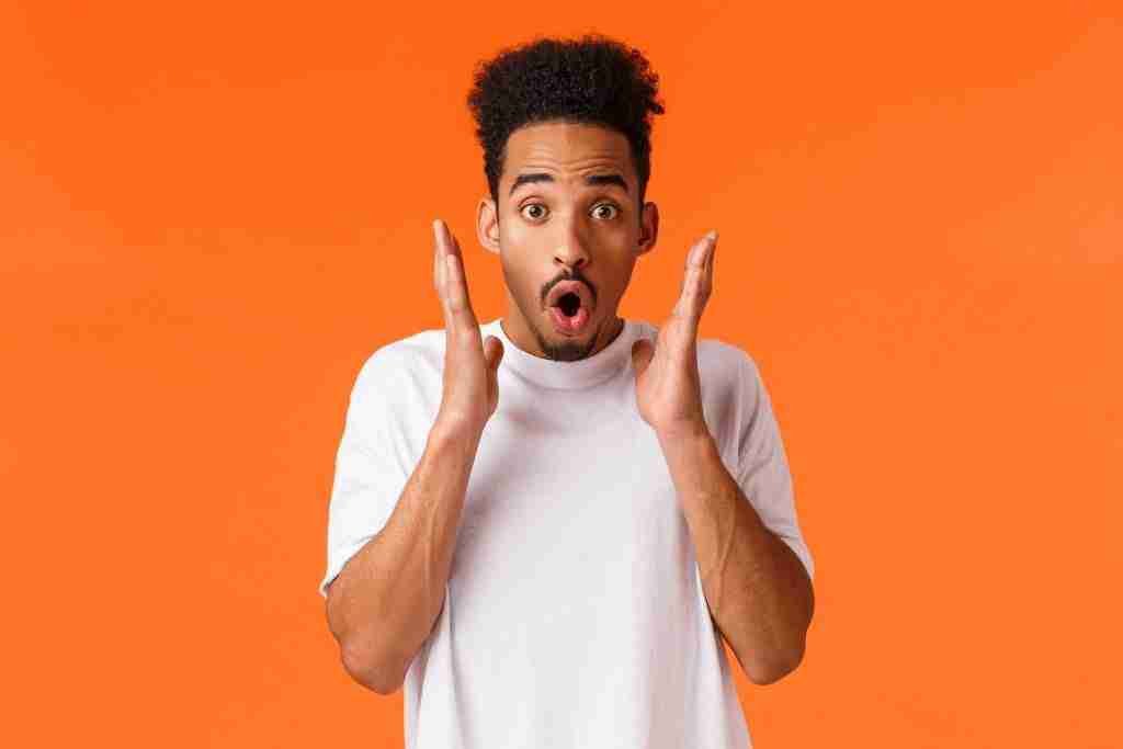 impressed startled african american guy seeing something awesome gasping wondered amused checking out discounts season sale attend stunning performance standing orange background 1