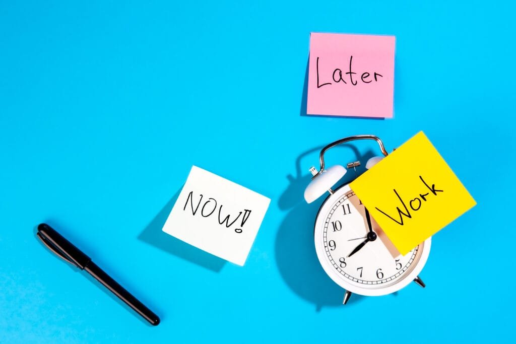 Using the Law of Attraction to Overcome Procrastination and Build Discipline 1 Alarm clock and colourful paper reminders on a blue background, top view. Work reminder concept
