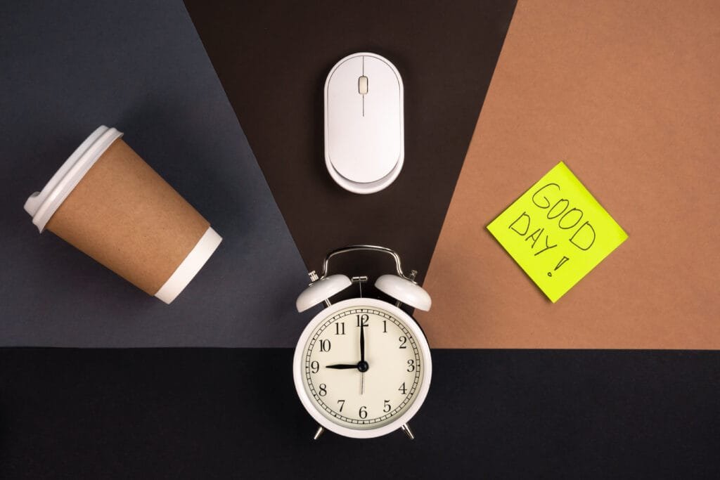 Using the Law of Attraction to Overcome Procrastination and Build Discipline 5 White alarm clock, computer mouse, paper cup and bright paper sticker, top view. Good day work concept. Discipline