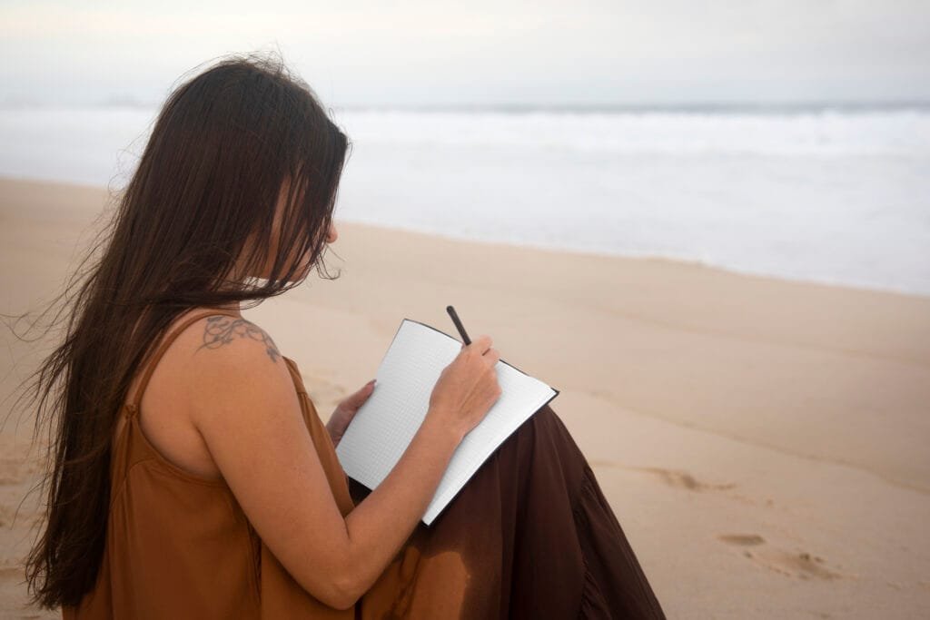 A woman writing in her journal on the beach