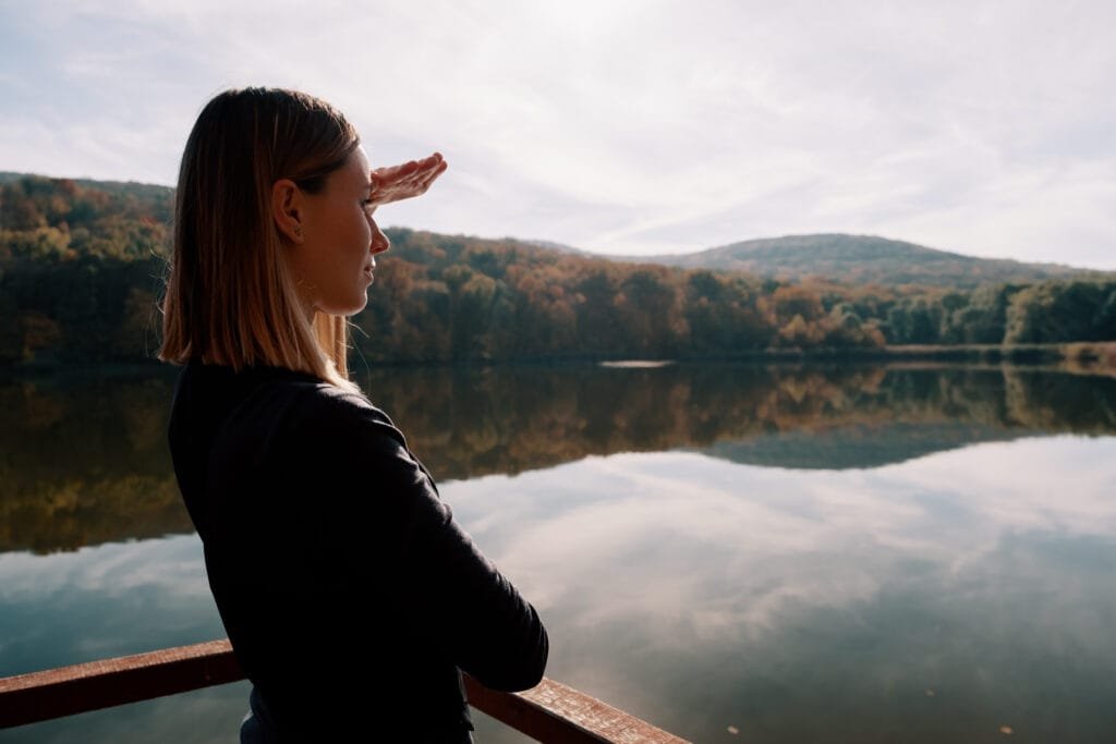 Using the Law of Attraction to Cultivate Inner Peace and Emotional Balance 6 Pretty woman enjoying the landscape view, sky, reflection in the morning lake in inner peace and balance